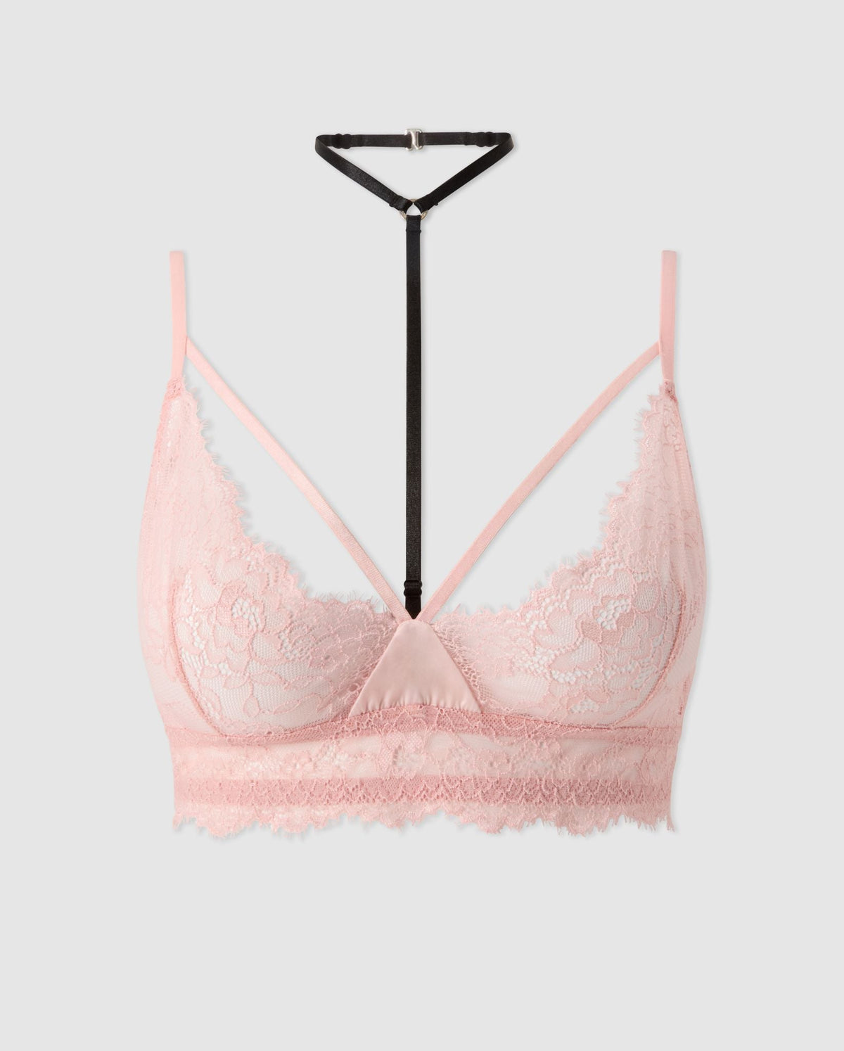 An powder pink lace triangle bralette with black and pink accessories.