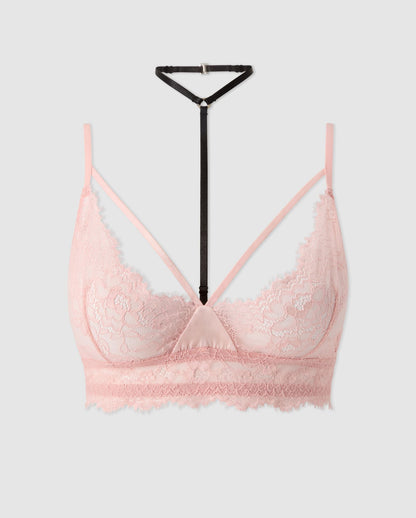 An powder pink lace triangle bralette with black and pink accessories.